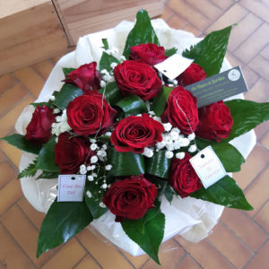 Bouquet de 12 roses rouges accompagnées de gypsophile, dans une bulle