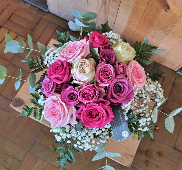 Bouquet de 15 roses dans les tons pastels, entourées de gypsophile et de verdure