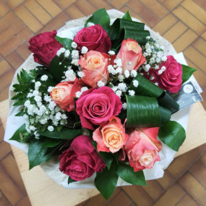Bouquet de 10 roses fuchsias et bicolores, accompagnées de gypsophile, dans une bulle